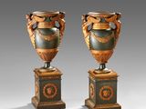 pair of antique vases on pedestals on a grey background