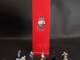 des figurines représentant un groupe de personnes debout devant une boîte rouge