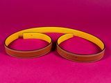 a pair of brown and yellow belts on a pink background