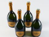 four bottles of champagne are lined up on a white surface