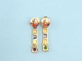 pair of gold earrings with multi colored stones on a blue surface