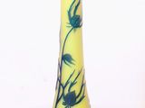un vase jaune orné de fleurs bleues, posé sur un fond blanc
