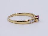 a close up of a gold ring with a pink stone