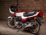 a red and white motorcycle parked in front of a brick wall