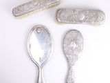trois cuillères en argent et un pinceau posés sur une surface blanche