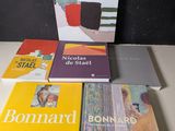Plusieurs livres sont empilés sur une table devant un mur noir.