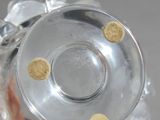 a silver vase with gold dots on it