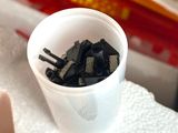 a plastic container filled with black chips and a fork