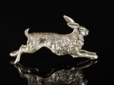 a silver rabbit figurine sitting on top of a black surface