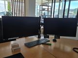 deux écrans d'ordinateur posés sur un bureau dans un bureau