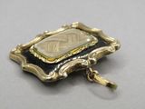 a close up of a gold and black broochle on a white surface