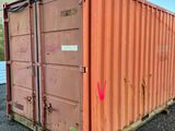 a red shipping container sitting in the middle of a gravel lot