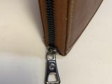 the zipper of a brown bag is open on a white surface