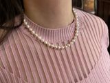 a woman wearing a pink sweater and a pearl necklace