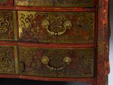 a red and gold chest of drawers with a clock on top