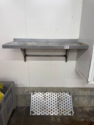 une étagère métallique fixée au mur, à côté d'une poubelle