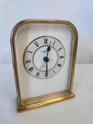 a small gold clock with roman numerals on it