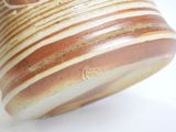 a brown and white striped vase on a white surface