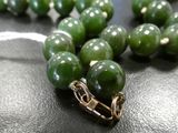 a close up of a green bead necklace on a black surface