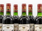 six bottles of red wine are lined up on a table
