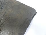 un morceau de métal portant une inscription, posé sur une surface blanche