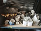 many cups and saucers on a shelf in the kitchen