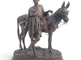statue représentant une femme à dos d'âne, un panier sur le dos