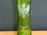 a green glass vase with a white bird on it on a table