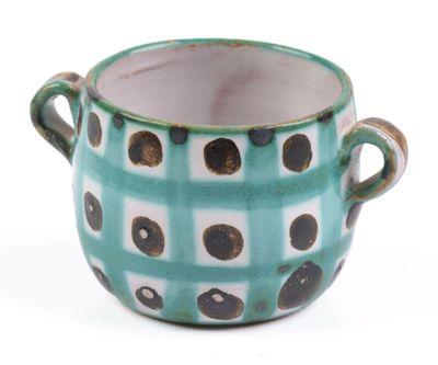a green and white cup with black dots on it