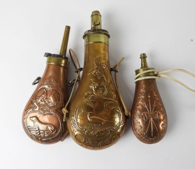trois décorations en forme de bouteille en laiton vieilli posées sur un fond blanc