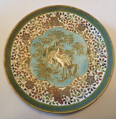 une assiette décorative sur laquelle figurent un oiseau et un arbre