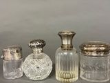 four glass jars with silver lids sitting on a table