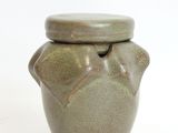 a small green jar with a lid on a white surface