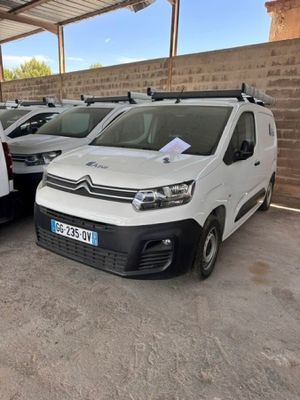 plusieurs fourgonnettes blanches garées sur un parking près d'un mur de briques
