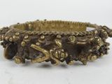 a close up of a gold bracelet on a white surface