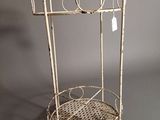 an old white metal rack with a basket on top of it