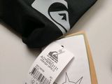 a black shirt with a label on it next to a cell phone