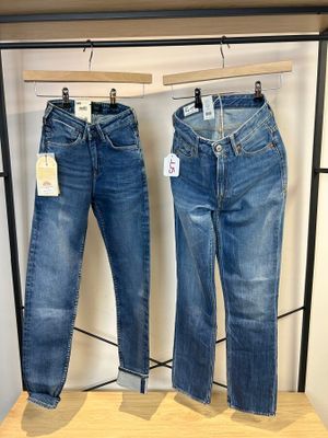 deux paires de jeans suspendues à un portant dans un magasin de vêtements