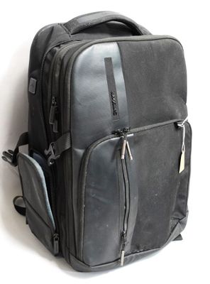 un sac à dos noir posé contre un mur blanc