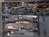 des couverts et des ustensiles dans un récipient en plastique posé sur une table