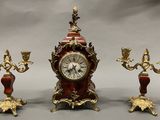 une horloge et trois bougeoirs placés les uns à côté des autres