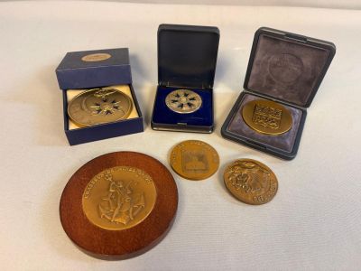 quatre médailles d'or et une boîte en bois posée sur un fond blanc