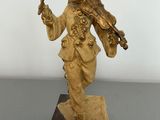 gold figurine of a man holding a sword on a wooden base