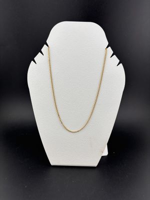a white mannequin with a gold chain on a black background