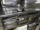many trays of food sitting on a shelf in the kitchen