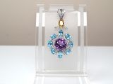 un pendentif en cristal violet et bleu présenté dans un écrin transparent