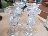 quatre bougeoirs en verre posés sur une table dans un magasin
