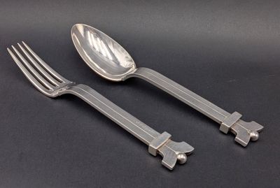 two forks and spoons on a black surface with a black background