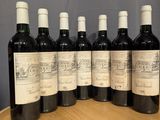 six bottles of wine are lined up on a wooden barrel