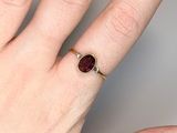someone is holding a ring with a red stone on it
